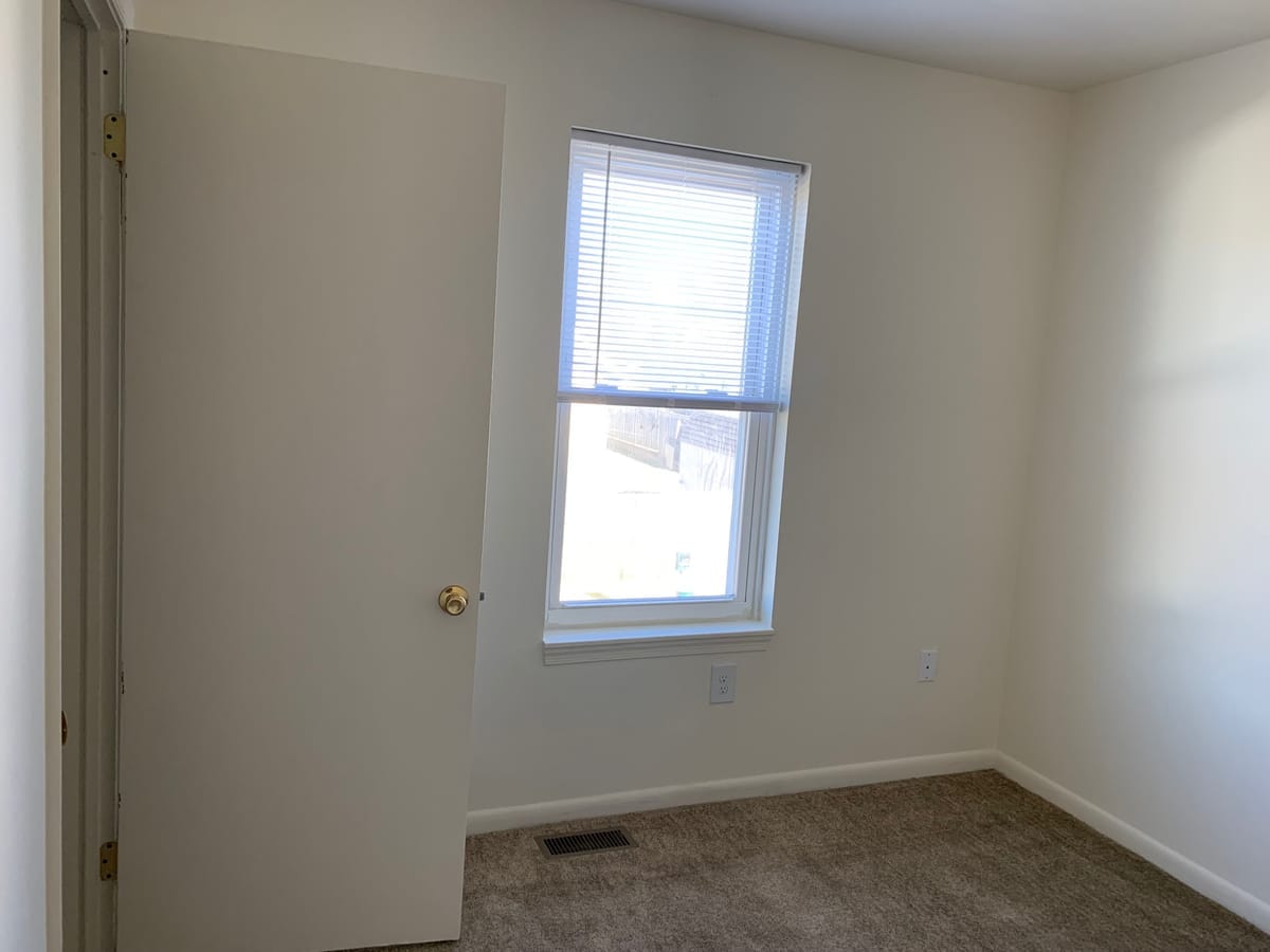 A second carpeted Taneytown Village bedroom with neutral walls and a window