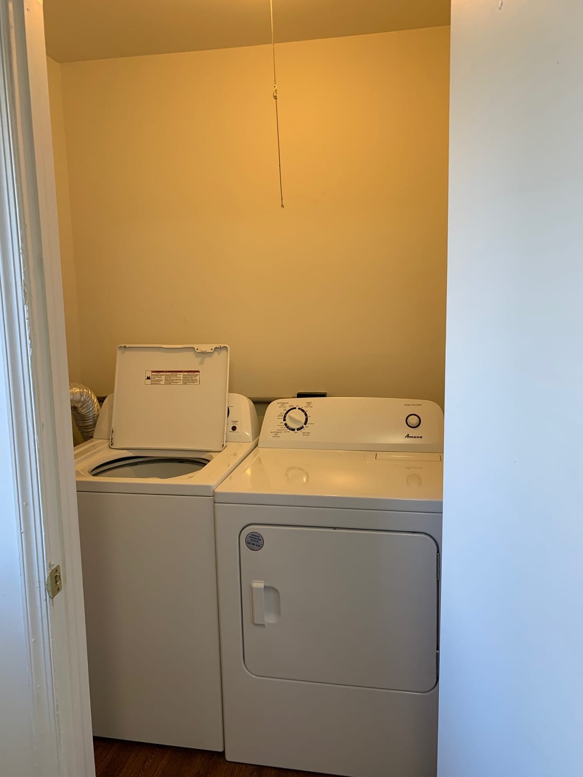 An in-unit laundry closet at Taneytown Village with a full-size top-load washer and a dryer side by side